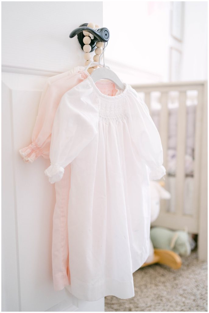 Handmade baby outfits hang in a nursery. Alpharetta Newborn Photographer Grace Emily documents precious nursery details.