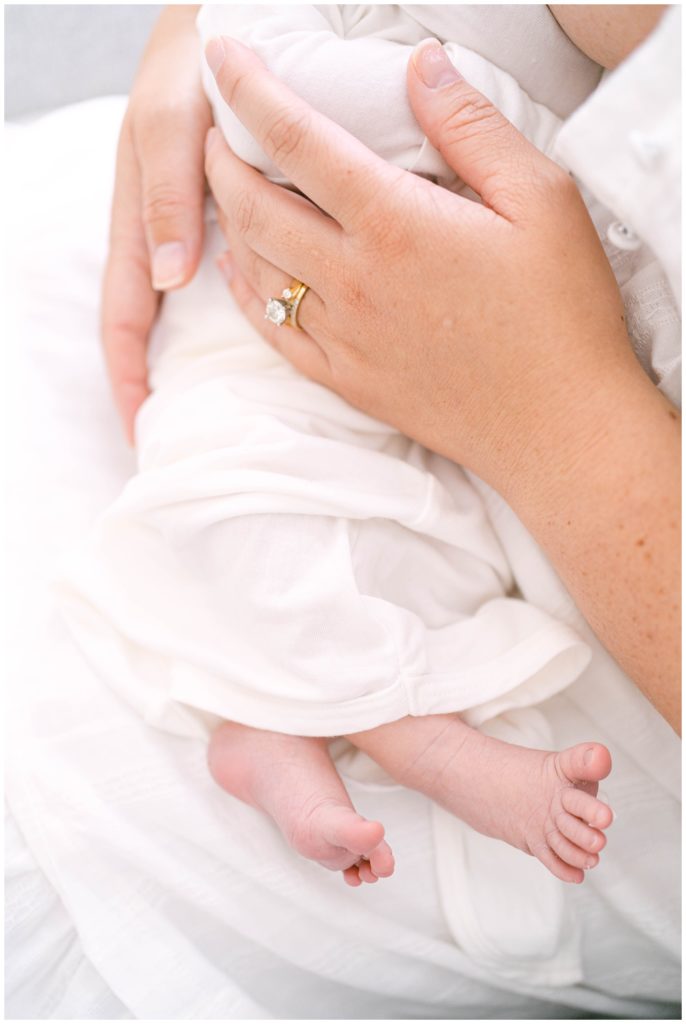 A mother's hands hold her new baby. Alpharetta Newborn Photographer Grace Emily documents these precious moments.