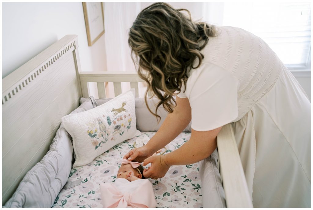 A mother tends to her baby in her crib. Grace Emily Photographer, an Alpharetta Newborn Photographer, specializes in in-home sessions.
