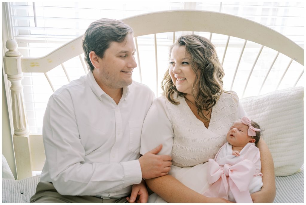 A new dad and mom hold their infant. Alpharetta Newborn Photographer Grace Emily photographs in-home newborn sessions.