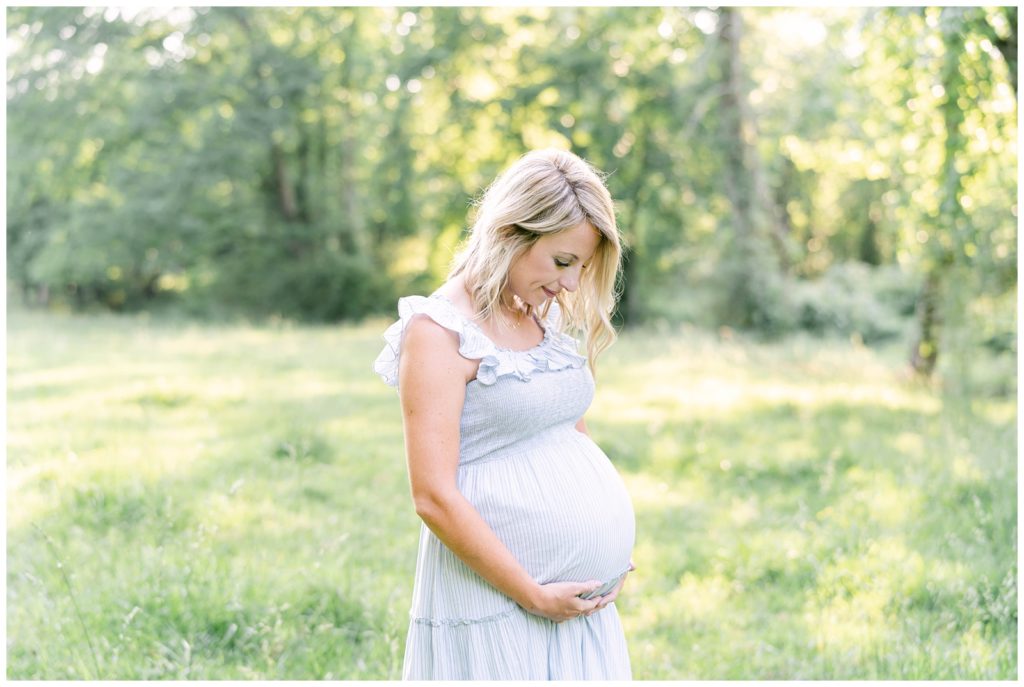A pregnant woman glances down at her growing belly. Atlanta Maternity Photographer Emily Grace Photography.