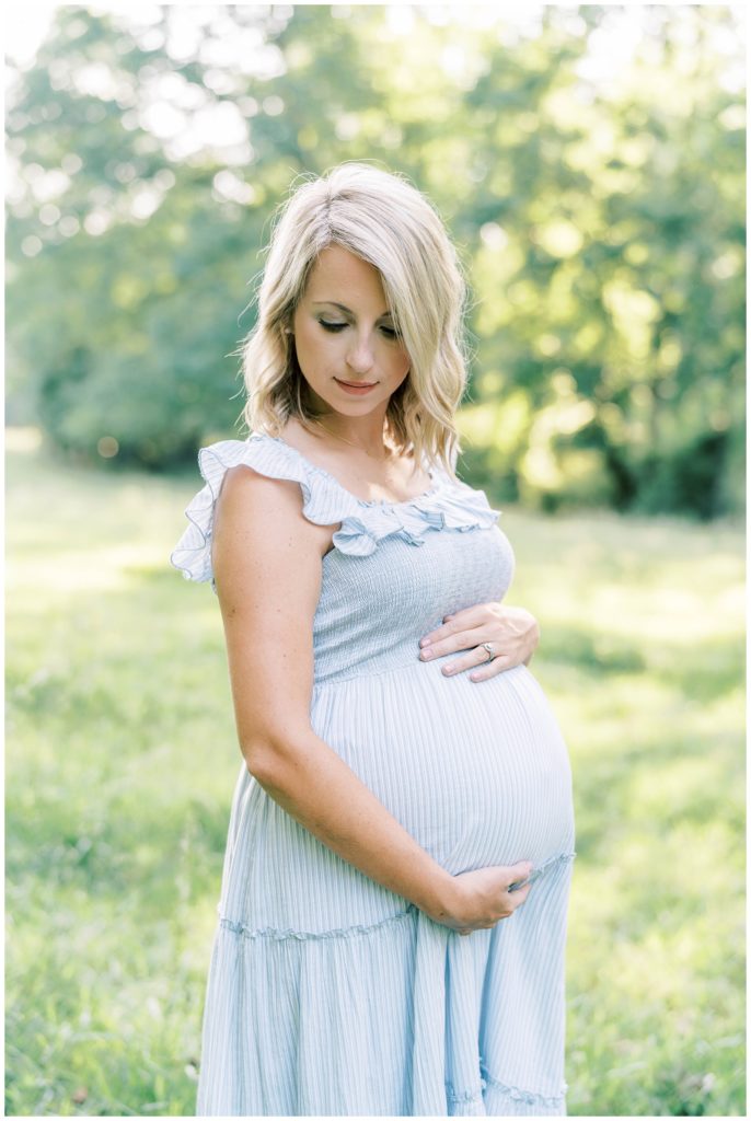 A pregnant mother glances down at her growing belly. Atlanta Maternity Photographer Emily Grace Photography.
