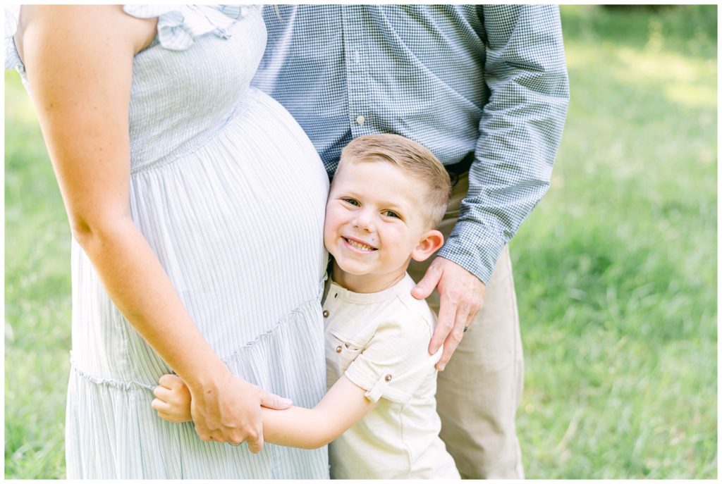 A smiling son nuzzles his mother's pregnant belly. Alpharetta Photographer Grace Emily documents the moment.