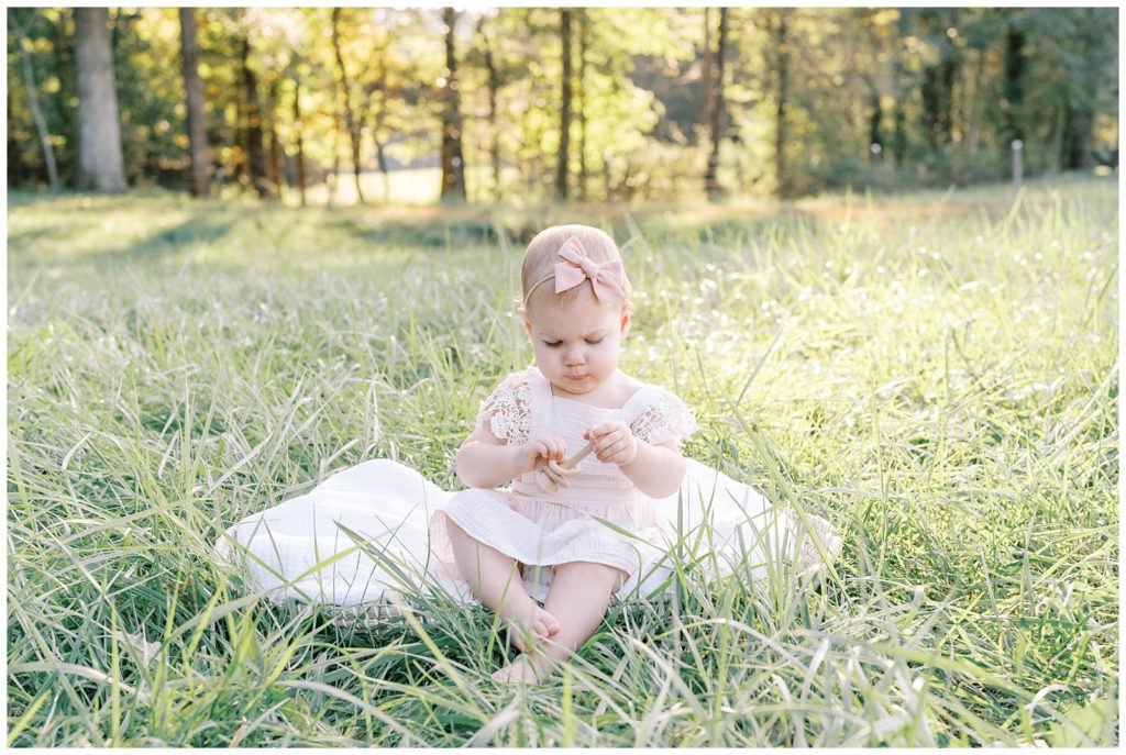 A toddler girl plays in the grass. North Georgia photographer Grace Emily captures the moment.