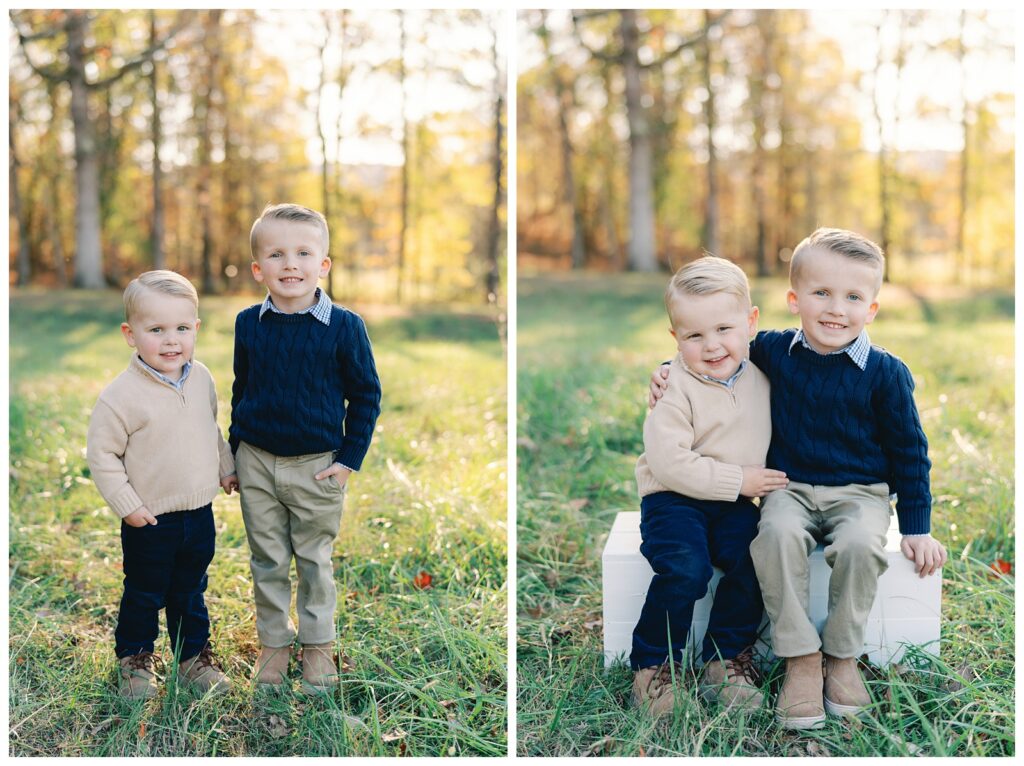Atlanta fall mini session of two children in a field of green grass lines by trees with yellow, red, and orange foliage by Grace Emily Photography.