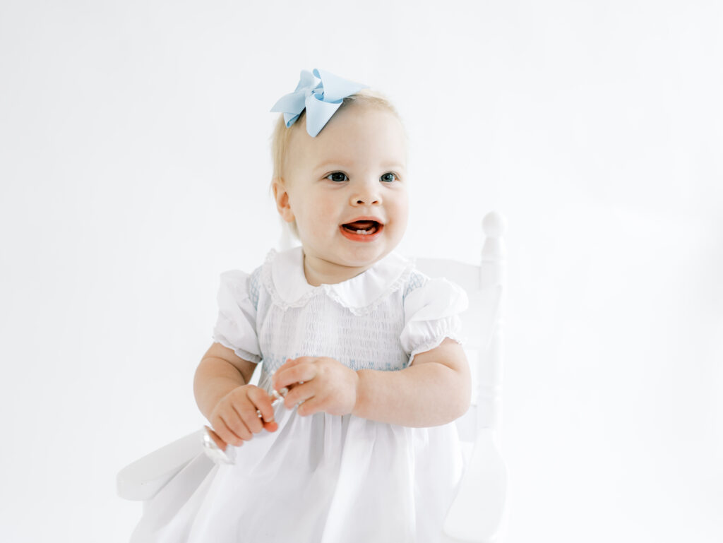 Little girl sitting in a white rocking chair during a portrait session with Atlanta photographer, Grace Emily Photography.