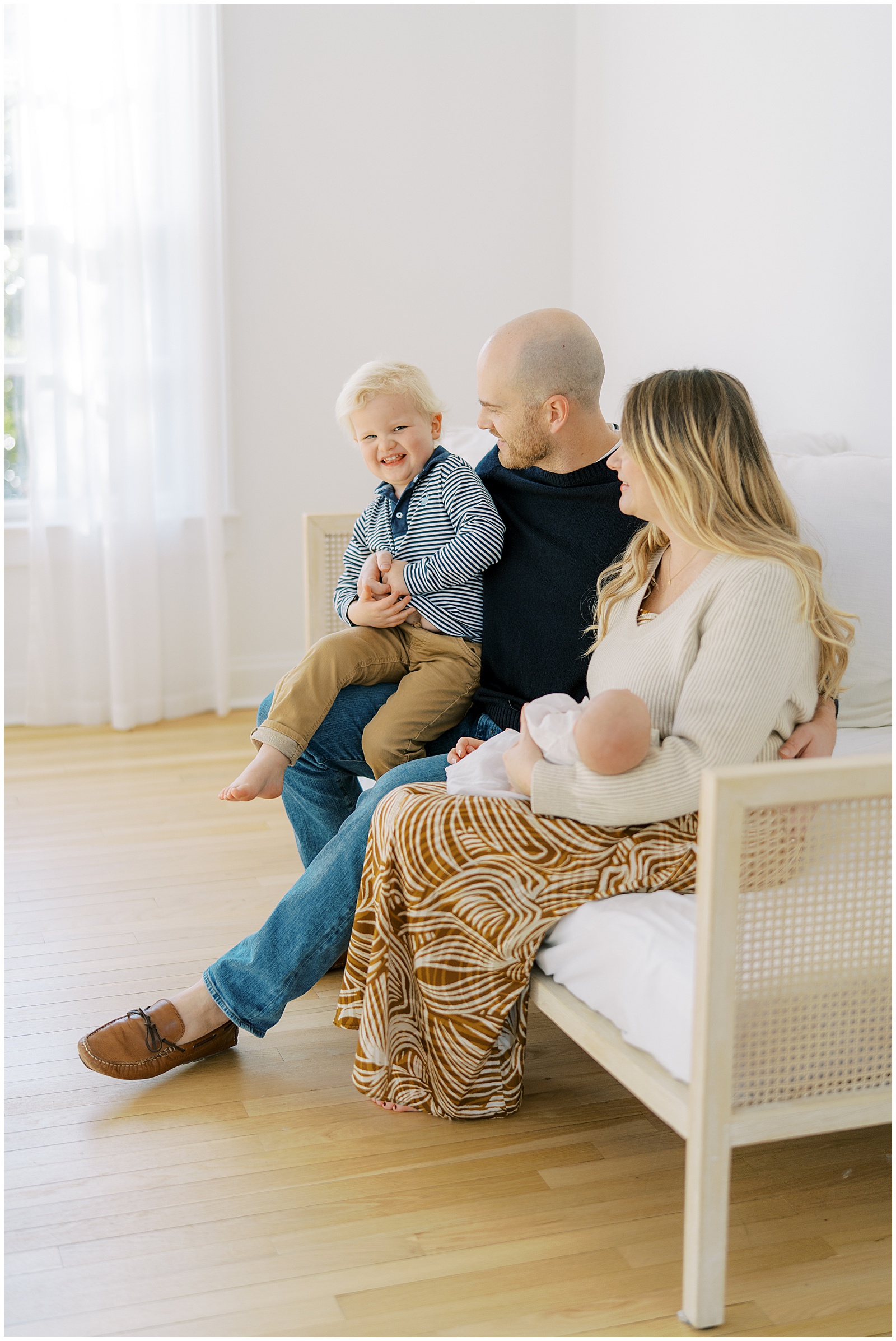 A family of four at a natural light studio having newborn portraits taken.